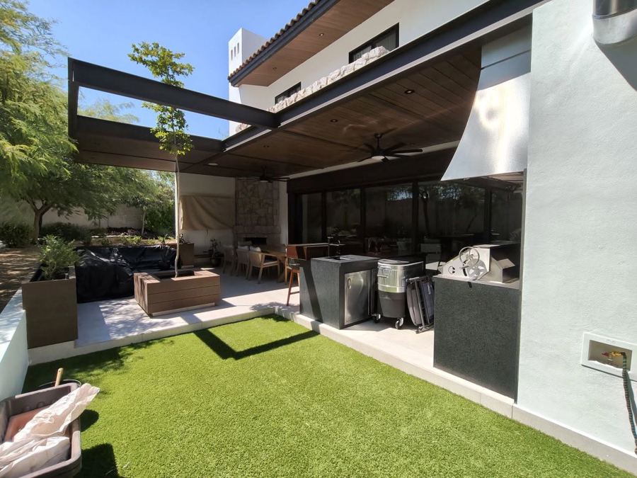 Terraza cubierta con asador, pérgola de acero y jardín